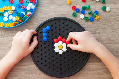 Kid 'in çok renkli mozaik parçalarını masada çaldığı en iyi görüntü. Çocuğun erken gelişimi için renkli plastik detaylar. Küçük bir çocuk için erken öğrenim ve eğitici oyuncaklar.