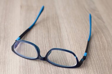 Kırık gözlük. Ahşap bir masada kırık bardaklar. Kırık gözlük çerçeveleri.