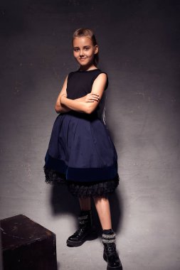 Stüdyoda 9-10 yaşındaki bir kızın kabarık etekli ve ceketli koyu arkaplanlı fotoğrafı. Çocuklar için şık resimler