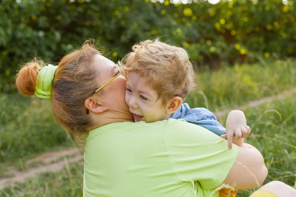 Eine Mutter und ein kleiner behinderter Junge umarmen sich und spielen in der Natur. Behinderungen. Kindheitslähmung. Mütter lieben. Glückliche Kindheit. — Stockfoto