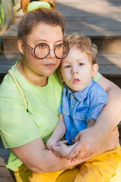 Eine Mutter und ein kleiner behinderter Junge umarmen sich und spielen in der Natur. Behinderungen. Kindheitslähmung. Mütter lieben. Glückliche Kindheit. — Stockfoto