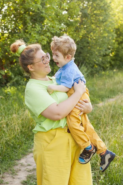 Eine Mutter mit einem kleinen behinderten Sohn ruht sich an einem sonnigen Tag im Stadtpark aus. Säuglingszerebralparese. Behinderungen. Rehabilitation eines behinderten Kindes. Sozialisation einer behinderten Person. — Stockfoto