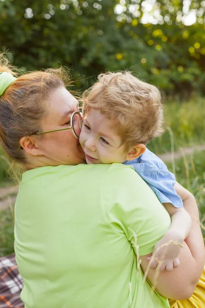Portrait d'une mère embrassant son jeune fils avec des besoins spéciaux dans un parc d'été. Invalidité. Paralysie infantile. Promenades estivales en plein air. — Photo