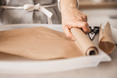 Kız, hafif bir fırın tepsisinde pişirmek için parşömen kağıdı açıyor. Evde yemek yapmak, el yapımı tatlılar..