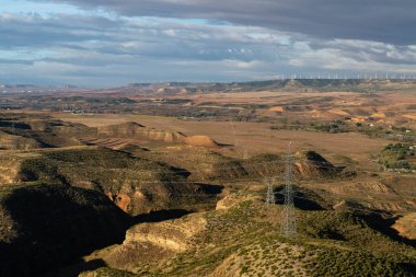 La Muela 'nın yel değirmenleriyle, birkaç kutup ve elektrik kablolarıyla yarı çöl vadisi Huerva' nın manzarası.