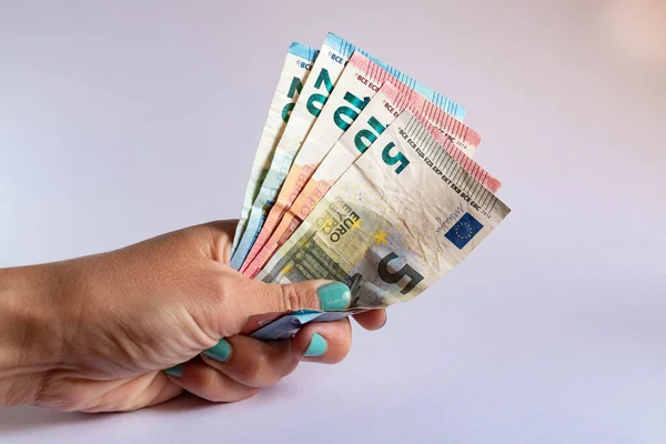 Hand holding several euro bills on white background