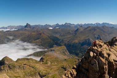 İki anonim dağcı Pireneler 'deki Aspe zirvesine ulaşıyor. İspanyol tarafında zirveler ve dağlar ve Fransız tarafında bir bulut denizi var.