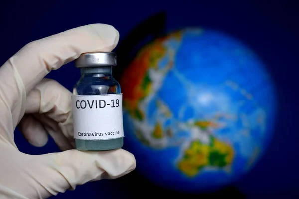 Coronavirus COVID-19 aşısı. Dünyanın arka planına karşı. Corona virüsü aşısını tutan doktor. 
