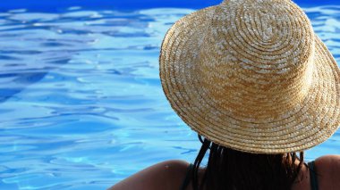 Havuzda hasır şapkalı bir kız. Tatil kavramı.