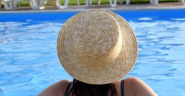 Havuzda hasır şapkalı bir kız. Tatil kavramı.
