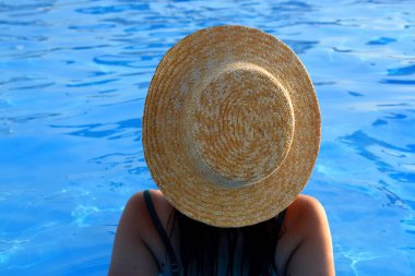 Havuzda hasır şapkalı bir kız. Tatil kavramı.