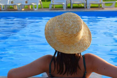 Havuzda hasır şapkalı bir kız. Tatil kavramı.