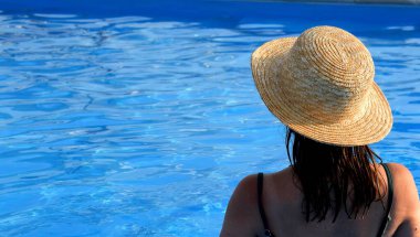 Havuzda hasır şapkalı bir kız. Tatil kavramı.