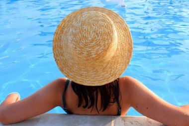 Havuzda hasır şapkalı bir kız. Tatil kavramı.