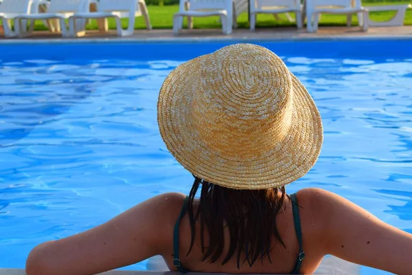 Havuzda hasır şapkalı bir kız. Tatil kavramı.