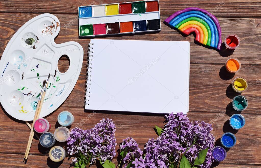 Rainbow, paints and lilac on a wooden background. Copy space