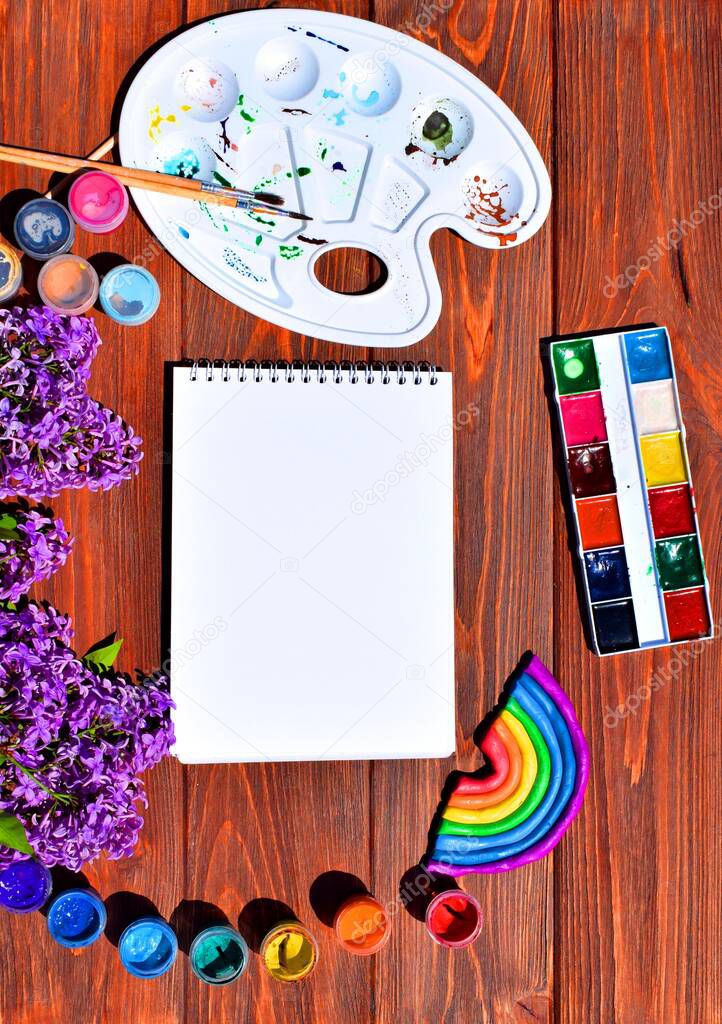 Rainbow, paints and lilac on a wooden background. Copy space