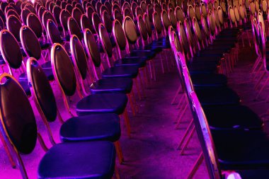 Konserden önce mağarada renkli sandalyeler. Konser salonundaki sandalyeler. Mağarada boş kırmızı koltuklar.