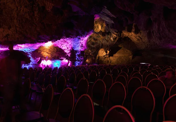 Colored chairs in the cave before the concert. Chairs in the concert hall. Empty rows of red seats in the cave. Colored scene.