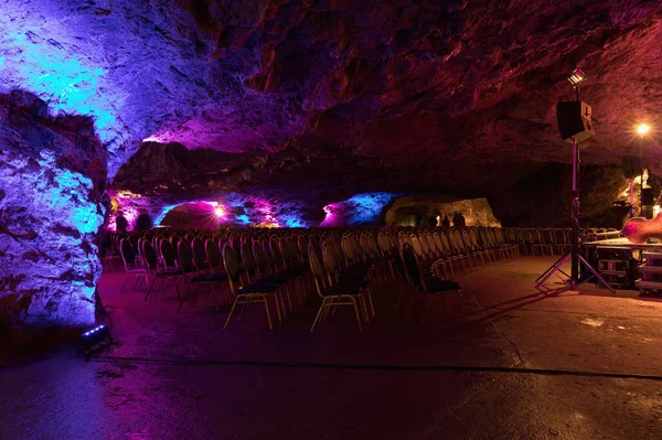 Colored chairs in the cave before the concert. Chairs in the concert hall. Empty rows of red seats in the cave. Colored scene.