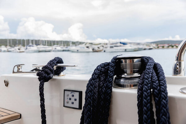 Detail of an anchor rope on a yacht. Mooring knot on the boat close up. Sealing knot close up. Stainless steel boat mooring cleat with knotted rope mounted on white yacht deck