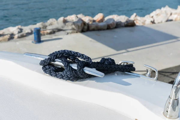 Detail of an anchor rope on a yacht. Mooring knot on the boat close up. Sealing knot close up. Stainless steel boat mooring cleat with knotted rope mounted on white yacht deck