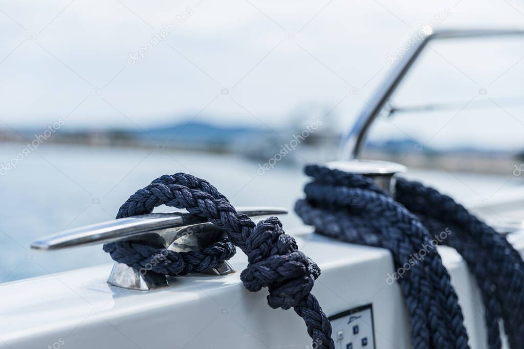 Detail of an anchor rope on a yacht. Mooring knot on the boat close up. Sealing knot close up. Stainless steel boat mooring cleat with knotted rope mounted on white yacht deck