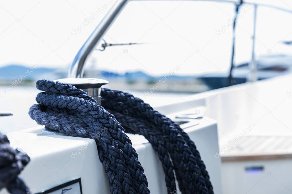 Detail of an anchor rope on a yacht. Mooring knot on the boat close up. Sealing knot close up. Stainless steel boat mooring cleat with knotted rope mounted on white yacht deck