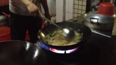 Cook wok içinde Asya erişte yapar. Çin'den kaynaklanan bir çok yönlü yuvarlak popolu pişirme alet. Asya yemek pişirme.