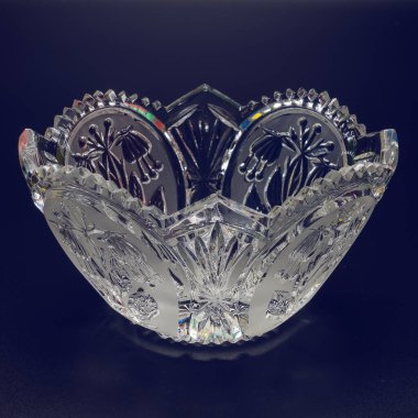 Küçük kristal vazo yakın plan. Kıvrımlı kenarlar, oyma, çiçek süsü. Kenarlarında farklı renkler parlıyor. Siyah arkaplan.