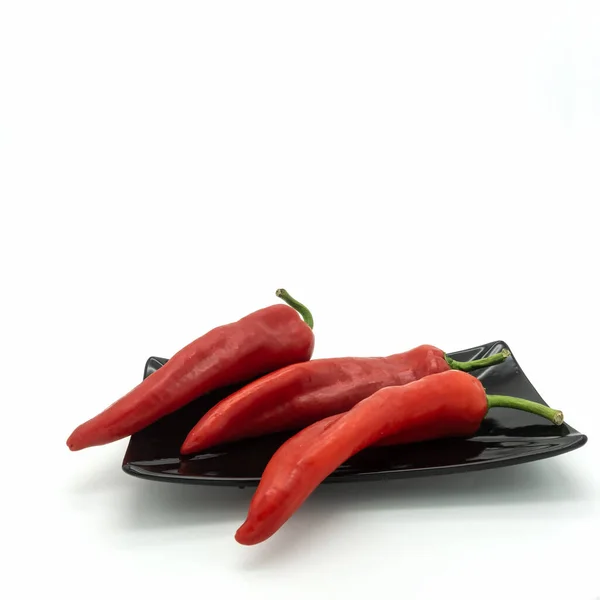 Tre Röda Paprika Svart Rektangulär Platta Ljus Glänsande Hud Gröna — Stockfoto