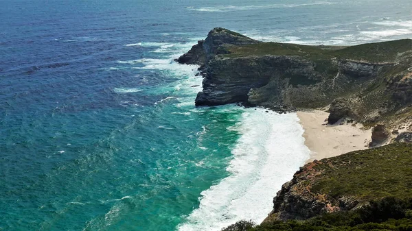 Efsanevi Ümit Burnu. Engebeli kayalık sahil şeridi ve gözlerden uzak küçük bir sahil. Atlantik Okyanusu 'nun turkuaz dalgaları kumda köpük bırakır. Güney Afrika
