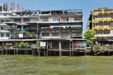 Nehrin kıyısında, kalelerin üzerinde konut evleri duruyor. Yüzünde çizikler, hasar ve küf var. Balkonlarda çamaşırlar kurur, bitkiler büyür. Bangkok 'ta. Tayland. Chao Phraya Nehri