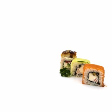 A set of three rolls: with eel, cucumber, salmon, close-up. Nearby is a sprig of curly parsley. Isolated over white background. Bottom right corner