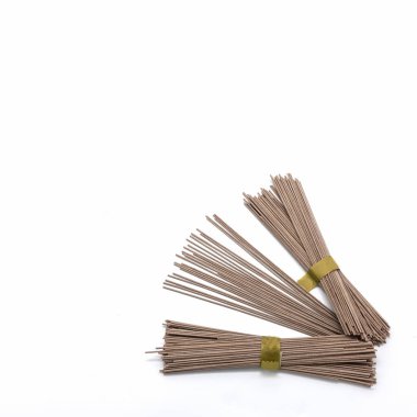 Beyaz arka planda karabuğday eriştesi. Paketler yeşil kurdelelerle bağlanmış. Birkaç spagetti gevşemiş.