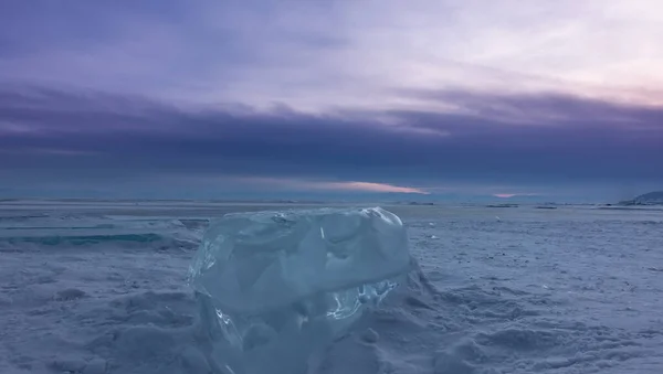 빛나는 청록색 얼음이 얼어붙은 호수의 눈덮인 표면에 떠다니고 배경에는 있습니다 — 스톡 사진