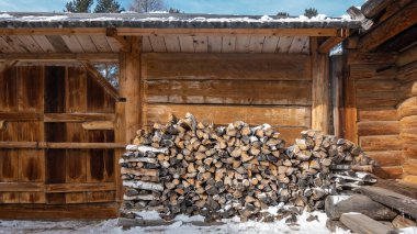 Kır evinin avlusuna, tahta çitin yakınına bir odun yığını konur. Kapı sürgülenmiş. Her yer karlı..