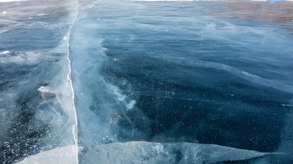 Hladkém Modrém Povrchu Ledu Táhnou Hluboké Pukliny Nějaký Sníh Zamrzlém — Stock fotografie