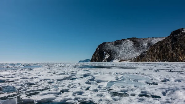 凍った湖には雪と氷が浮かんでいる 青い空を背景に 植生のない花崗岩の岩 晴れた日の冬 シベリアだ バイカル — ストック写真