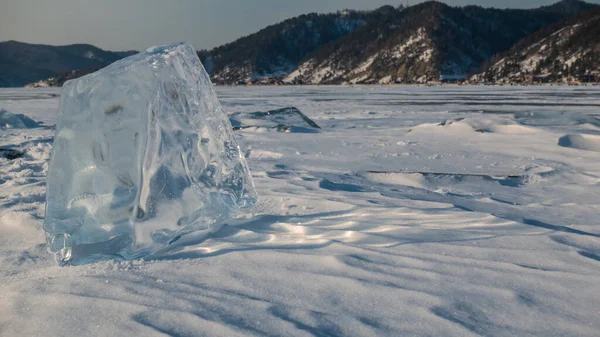 透明闪亮的冰片特写 阳光照在边缘 阴影照在雪地上 背景冰封的湖泊 贝加尔湖冬季 — 图库照片