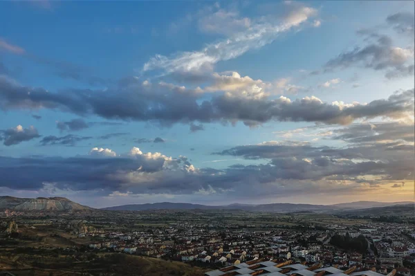 카파도키아의 하늘에는 황금빛으로 빛나는 구름들이 계곡에는 집들이 지평선에 실루엣 — 스톡 사진