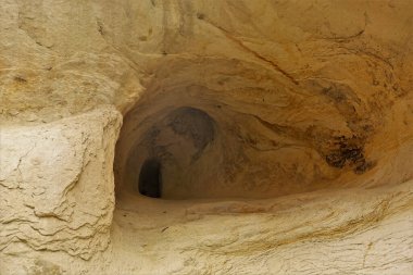 Mağara, Kapadokya 'nın kumtaşı uçurumuna oyulmuş. Yuvarlak kasalar ve derinlerde dar bir karanlık açıklık. Yakın plan. Taş dokusu. Türkiye