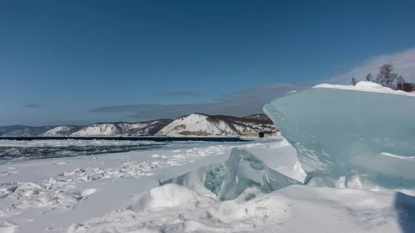 雪の降り方と氷の塊は氷結していない川の岸にある 鋭いエッジを持つターコイズ光沢のあるハンモック 遠くでは 山の範囲の背景に シベリアだ アンガラ — ストック写真
