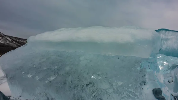 绿松石冰在多云的天空背景下发出嗡嗡声 在边缘上闪耀着太阳 地面上的雪 贝加尔湖 — 图库照片