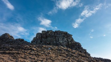 Mavi gökyüzüne karşı bitki örtüsünden yoksun pitoresk bir granit kaya. Taşlarda çatlaklar görülebilir. Sibirya