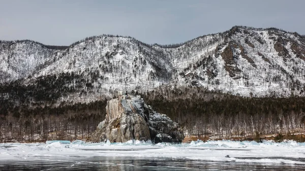花岗岩一种花岗岩岩石 其轮廓奇特 顶部平坦 耸立在冰冻的湖面之上基座上有雪 冰上的倒影背景是白雪覆盖的山脉 贝加尔湖 — 图库照片