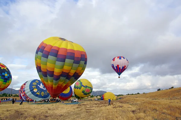 Heißluftballon schwebt über Weinbergen und Obstplantagen während Temecula Ballon und Weinfest in Kalifornien. Diese jährliche Veranstaltung bietet 2 Tage Ballonfahrten am Morgen, Musikfestival und Weinprobe. — Stockfoto