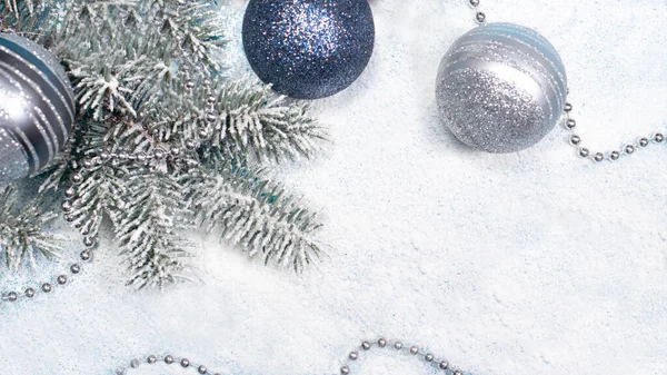 Branche d'épinette avec des jouets de Noël et des perles sur un fond blanc recouvert de neige avec une place pour le texte de copyspace. Une carte de vacances. — Photo
