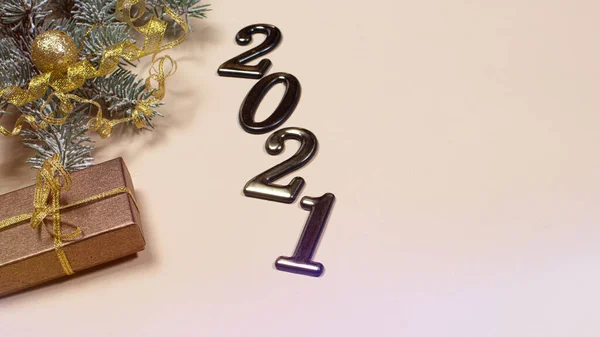 New Year\'s card with figures 2021, gift and spruce branch on a beige background with a place for copyspace text. Christmas, year of the bull.