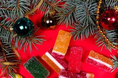 Marmelat reçelleri ve kırmızı arka planda bir oyuncak ve kurdeleli ladin dalı. Şekerlemeler için kırmızı arkaplanda bir pankart